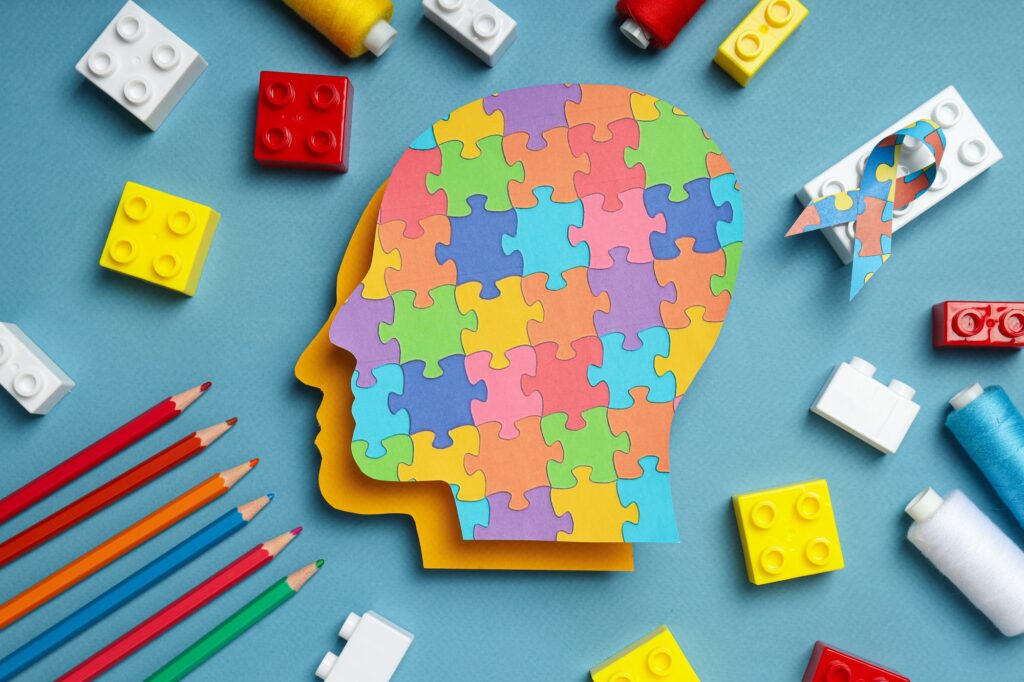 Paper human heads with colorful puzzle pieces on a light background. World autism day concept